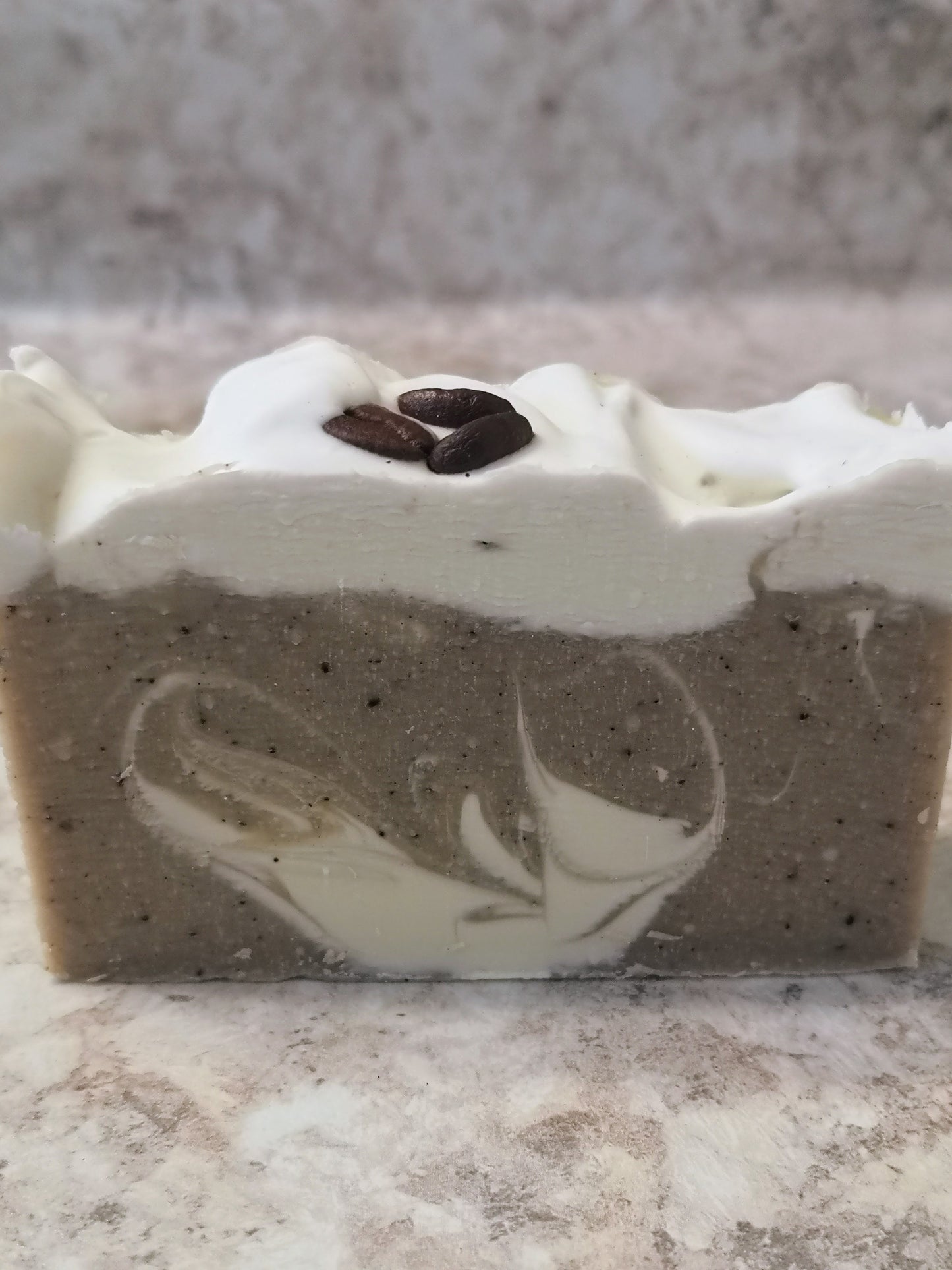 One bar of coffee coloured soap with flecks of coffee and white swirl and creamy white top with three coffee beans.