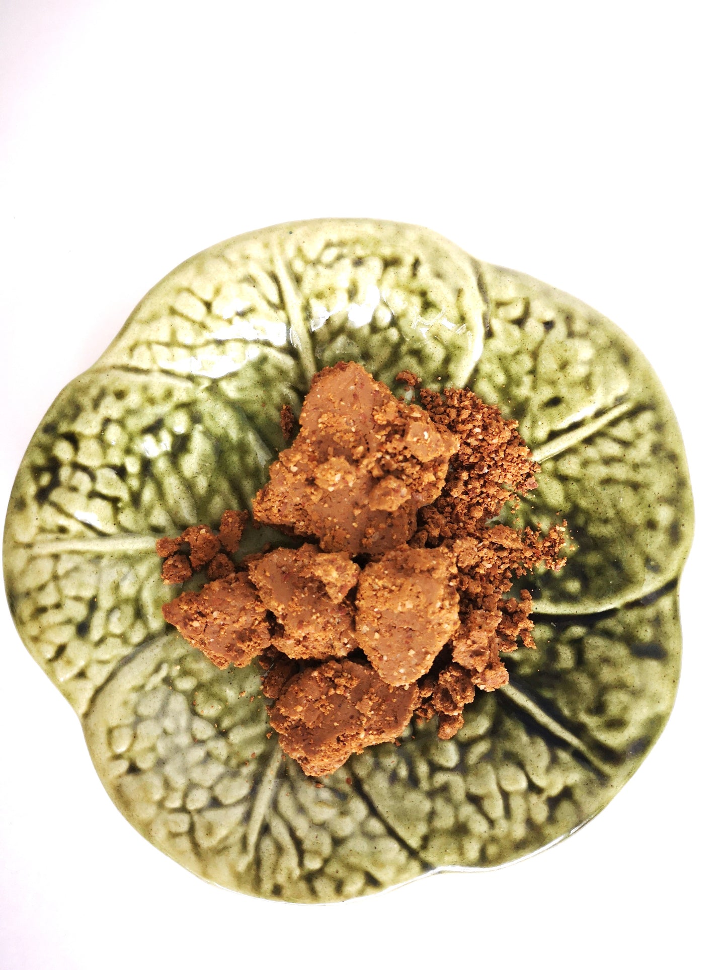 Brown pieces of facial cleanser in a green leave bowl.