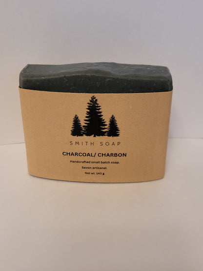 A black bar of charcoal soap with a craft paper cigar wrapper. Smith soap charcoal soap.