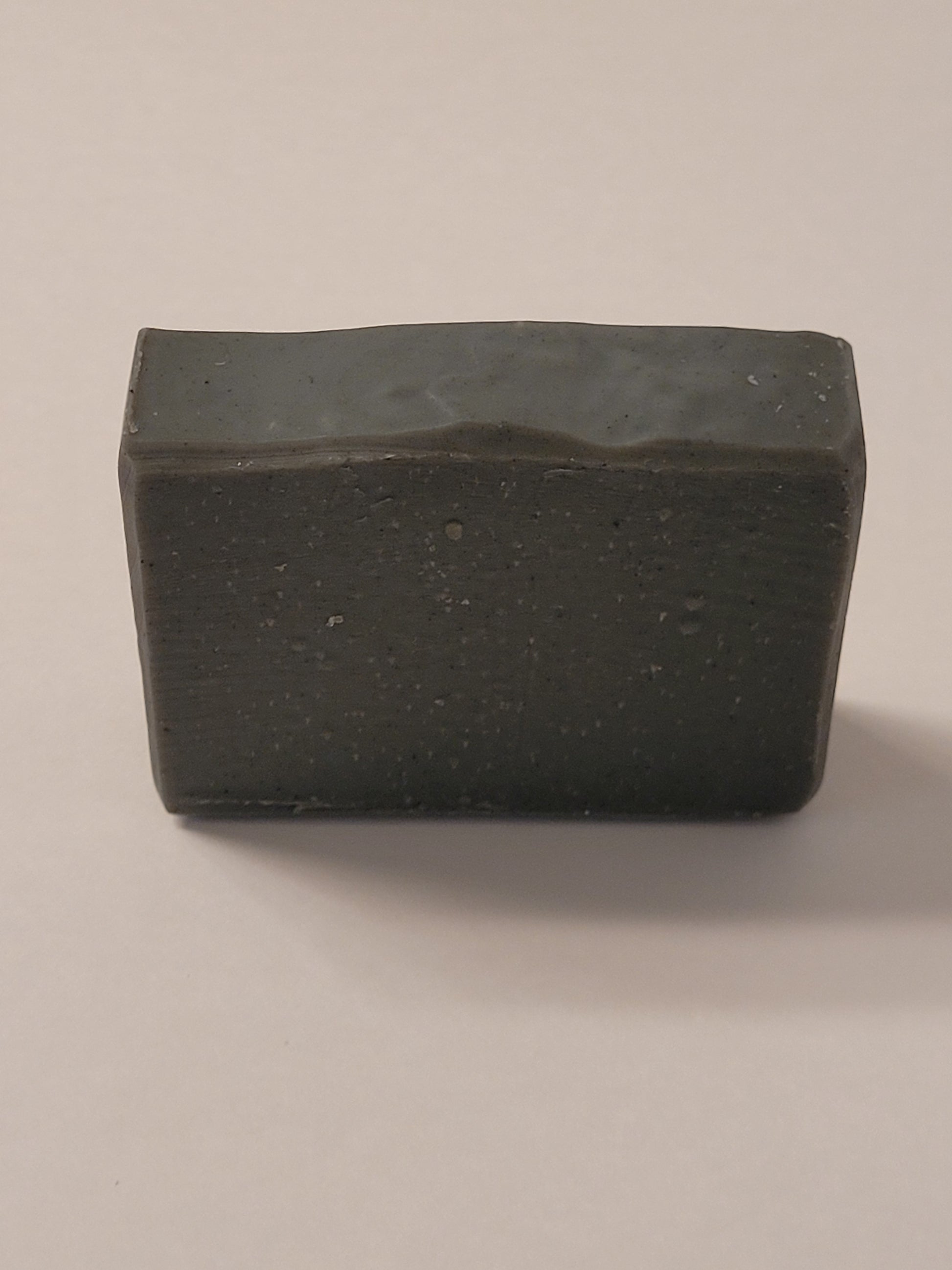 a plain black bar of soap on a grey background. 