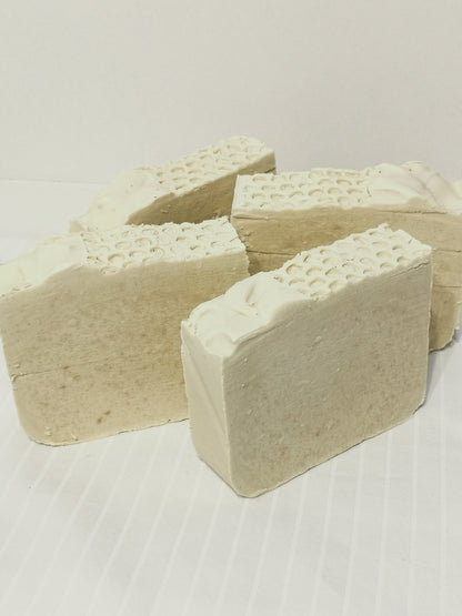 4 bars of creamy white soap with textured top on an off-white background. 