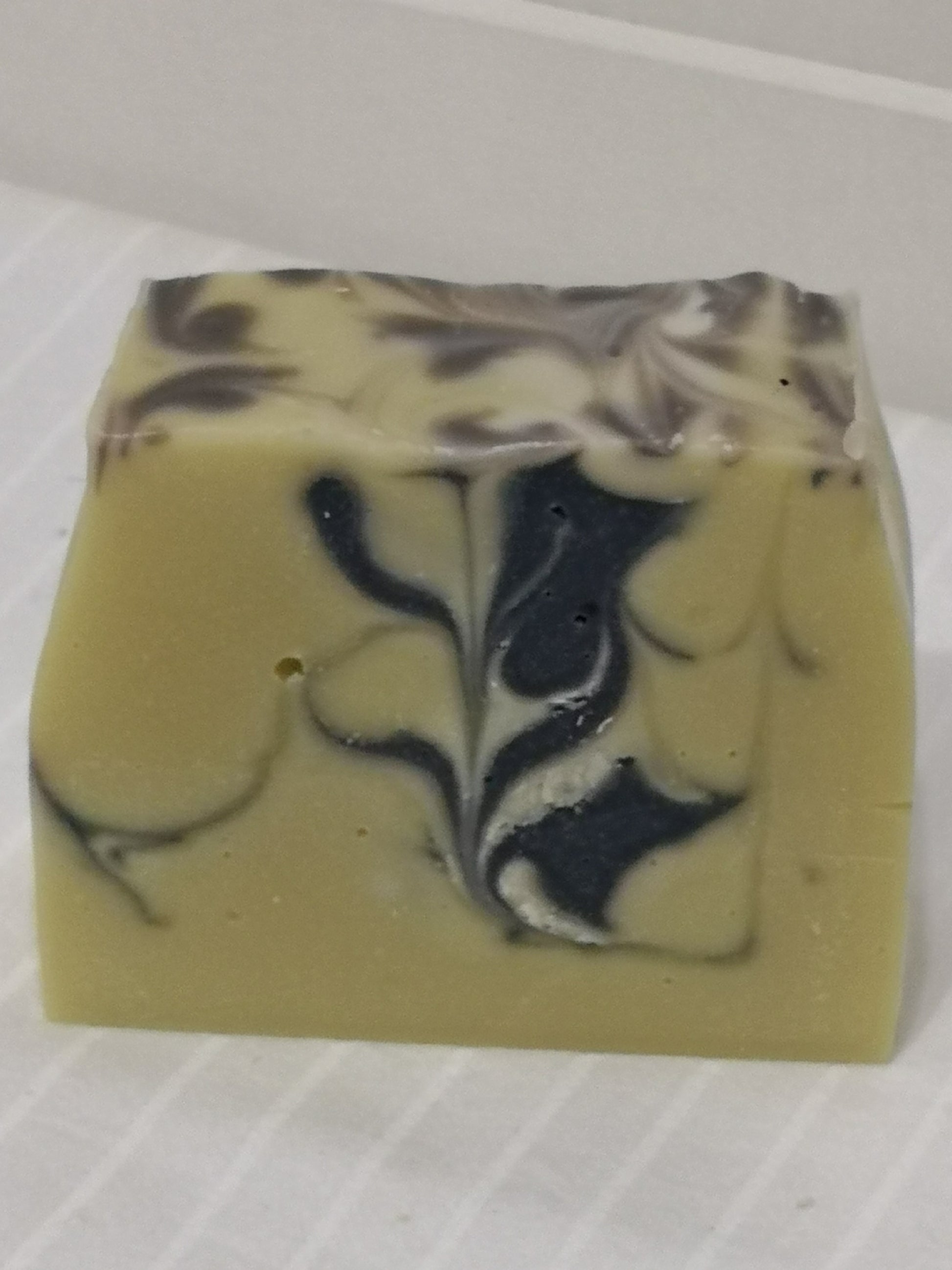 Close up of one bar of creamy soap featuring dark blue swirl design. 