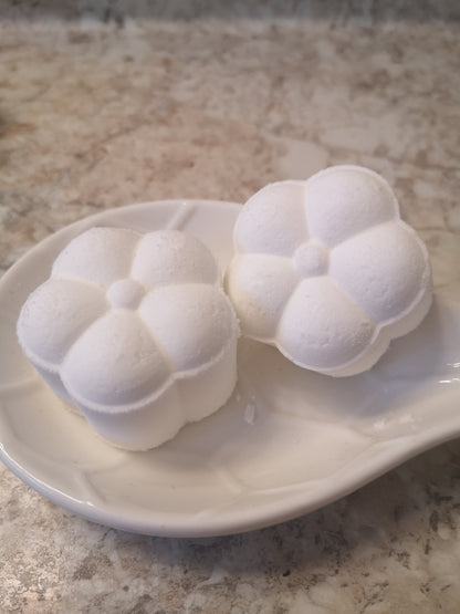 Two white flower shaped steamers on a white ceramic dish sitting on a brown textured counter top.