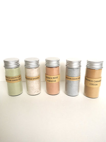 5 glass tubes with silver aluminum caps. One green french clay, one white rhassoul kaolin clay, one pink french rose hibiscus, one grey kaolin charcoal and one tan french caramel cocoa